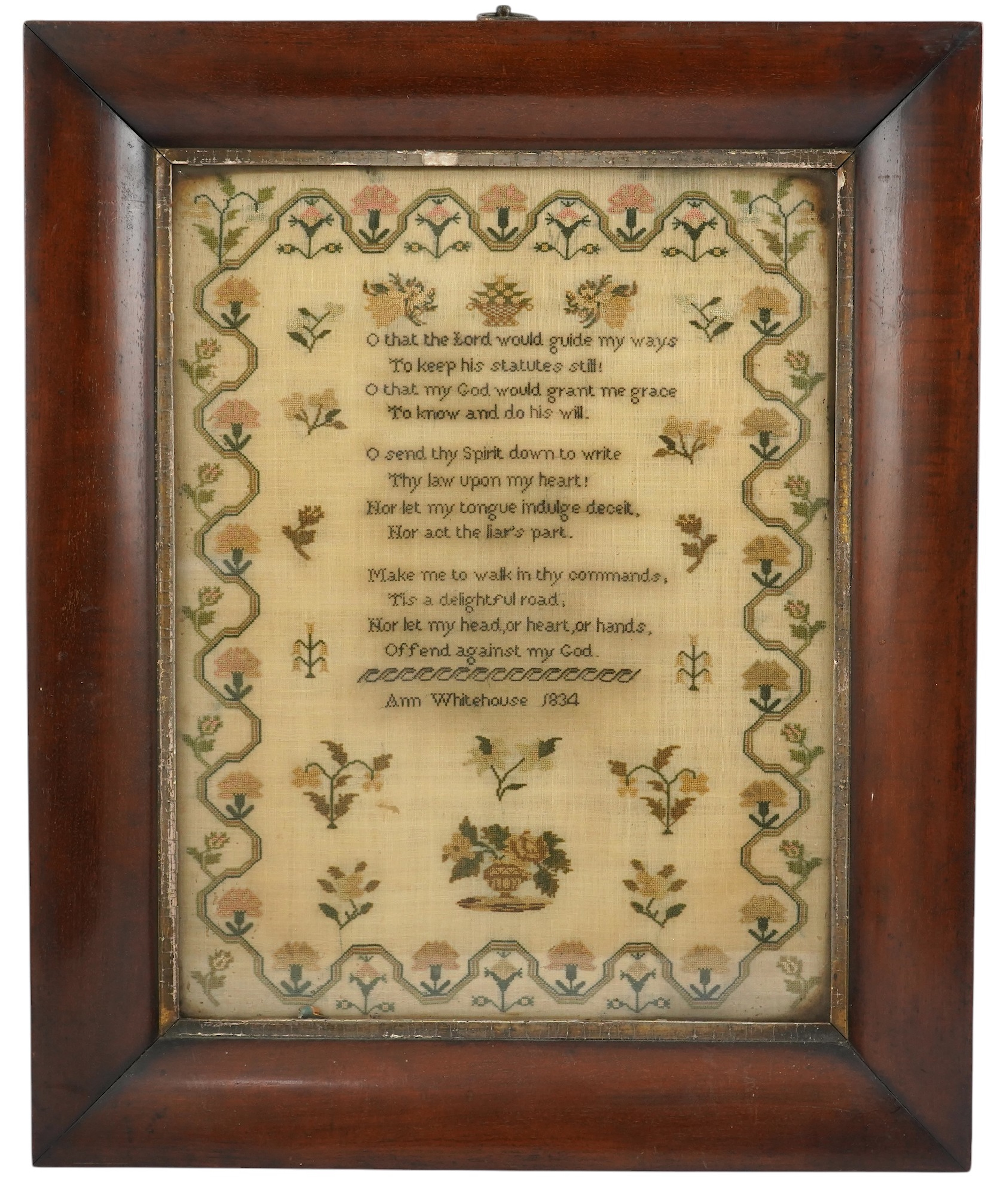 A wide mahogany framed sampler by Ann Whitehouse dated 1834, worked in coloured silks on a fine linen ground, in small stitches, bordered with a geometric stylistic vining pattern, set with a central verse, above her nam